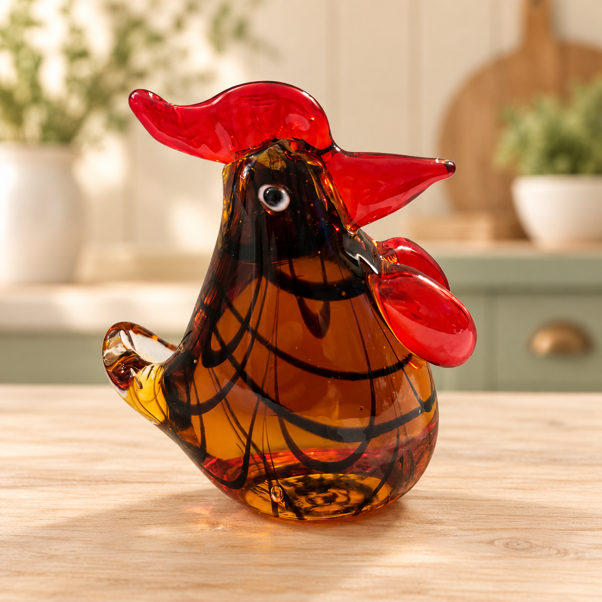 Amber glass rooster with looping black lines and ruby-red comb on a farmhouse kitchen background